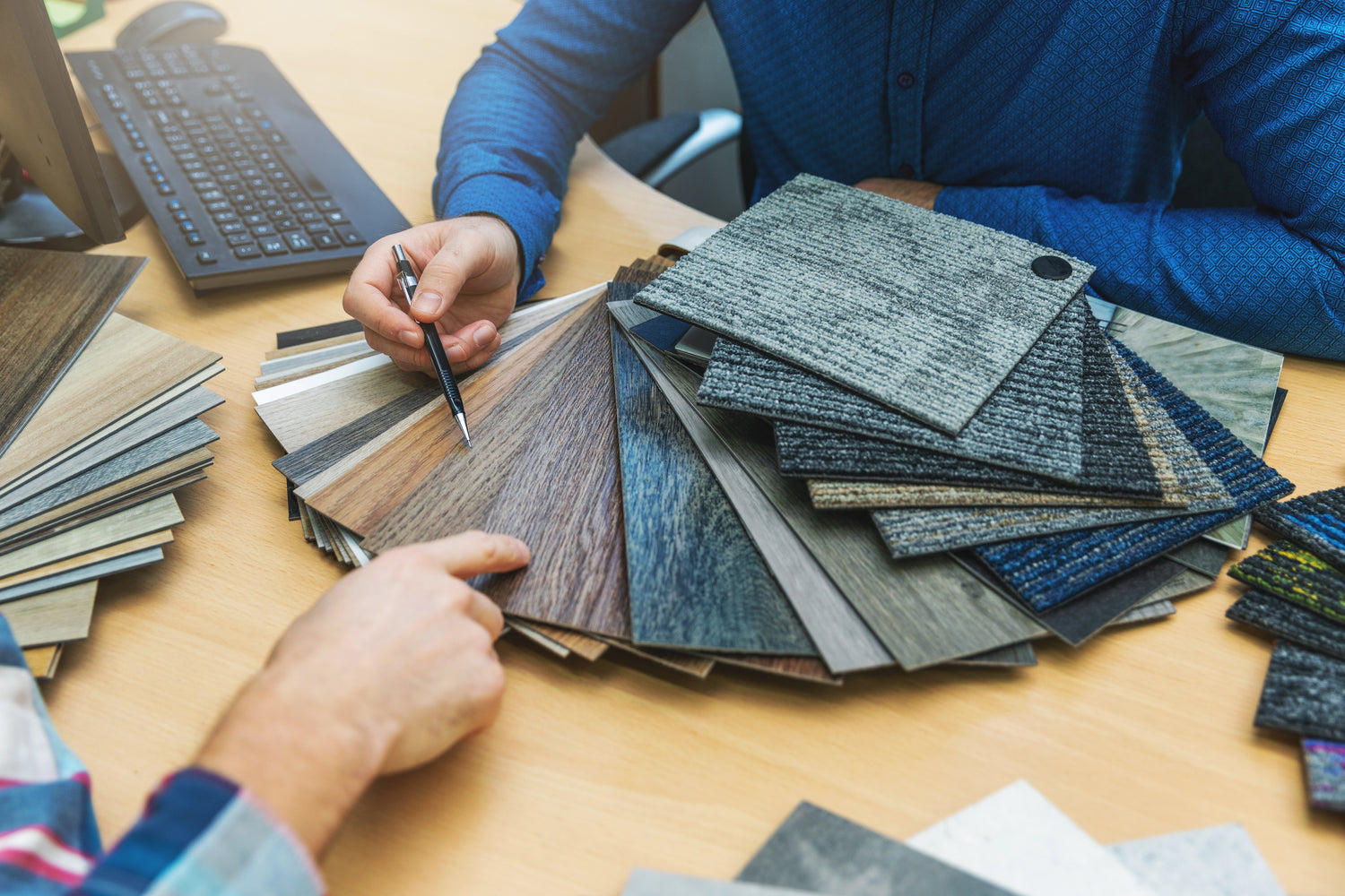Blick auf einen Schreibtisch und Musterkarten von Bodenbelägen wie Teppich, PVC und Laminat