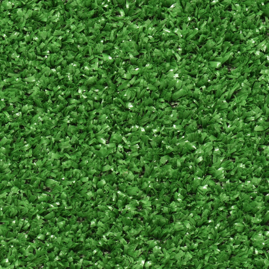Le gazon artificiel vert dense recouvre le sol, crée une texture uniforme et donne l'impression d'une pelouse naturelle.